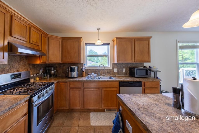 1591 Lillyview Ct SW, Wyoming, MI 49509 - kitchen with appliances with stainless steel finishes, under cabinet range hood, brown cabinets, decorative backsplash, and decorative light fixtures