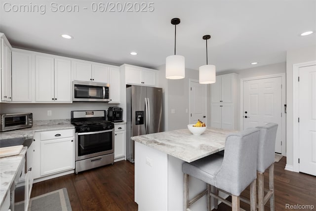 3923 Maple Ln, Auburn Hills, MI 48326 - kitchen featuring appliances with stainless steel finishes, dark wood-style floors, white cabinetry, a kitchen island, and light stone counters
