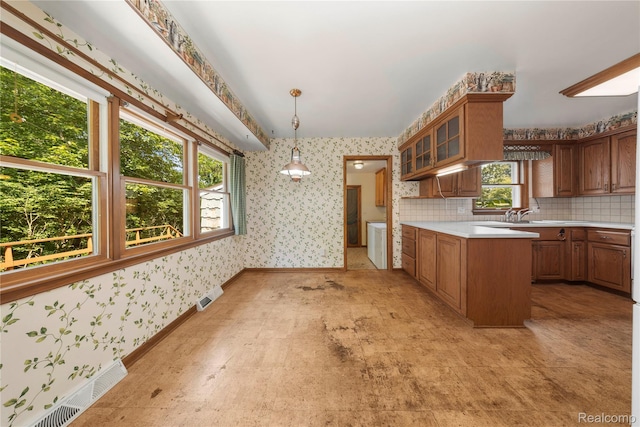 26165 Hidden Valley Dr, Farmington Hills, MI 48331 - kitchen featuring wallpapered walls, light countertops, glass insert cabinets, brown cabinets, and pendant lighting