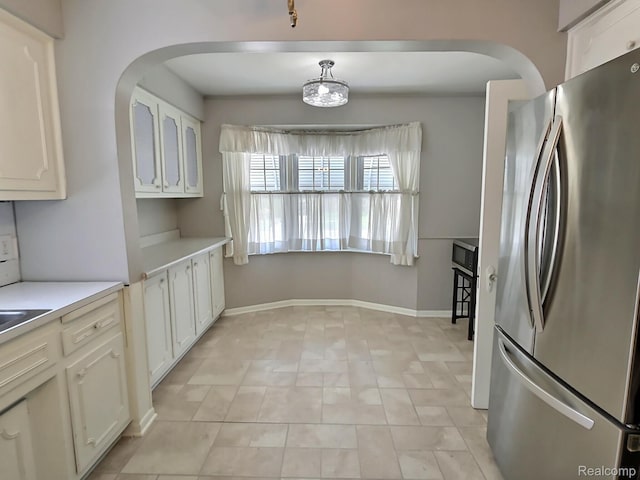 1154 Lincoln Ave, Rockwood, MI 48146 - kitchen featuring freestanding refrigerator, arched walkways, white cabinets, and light countertops