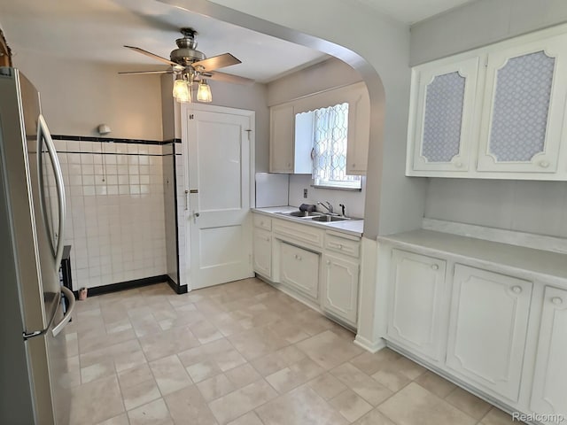 1154 Lincoln Ave, Rockwood, MI 48146 - kitchen with freestanding refrigerator, a ceiling fan, light countertops, white cabinets, and arched walkways