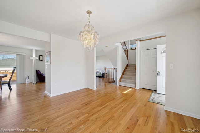 61 Old Carriage Ln, Lapeer, MI 48446 - unfurnished living room featuring a chandelier, light wood-style floors, and stairs