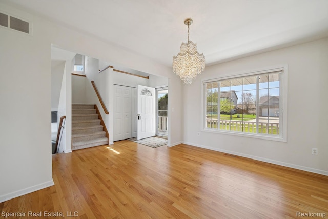 61 Old Carriage Ln, Lapeer, MI 48446 - spare room with a chandelier, stairs, and light wood finished floors