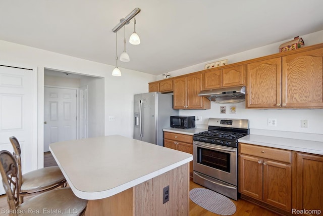 61 Old Carriage Ln, Lapeer, MI 48446 - kitchen with appliances with stainless steel finishes, under cabinet range hood, light countertops, a breakfast bar, and pendant lighting