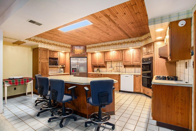 520 Groat Rd, Dowling, MI 49050 - kitchen with black appliances, light countertops, a breakfast bar area, backsplash, and light tile patterned floors