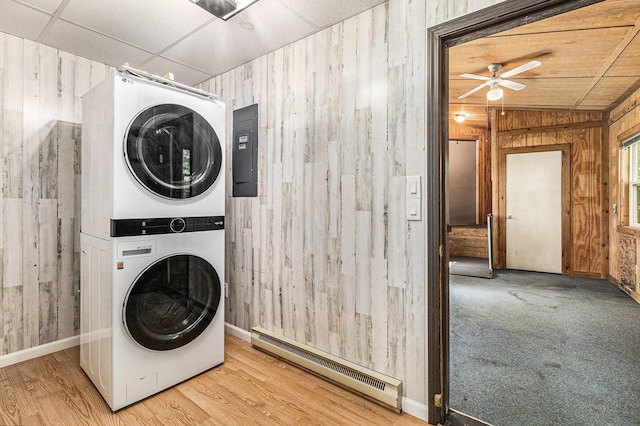 300 Basswood Ter, Brooklyn, MI 49230 - washroom with stacked washer and clothes dryer, baseboard heating, wooden walls, ceiling fan, and wood finished floors
