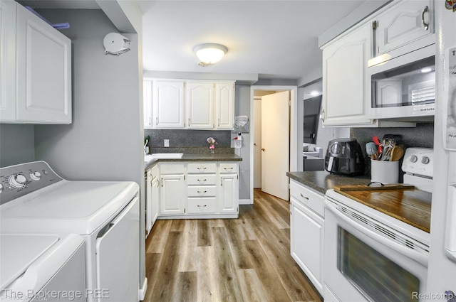 4462 Dye Rd, Swartz Creek, MI 48473 - kitchen with white electric range oven, stainless steel microwave, washing machine and dryer, white cabinets, and light wood-style flooring