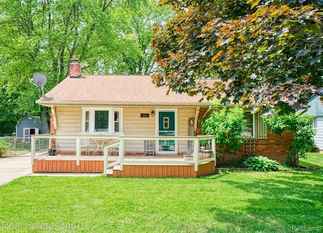 5320 Leland St, Brighton, MI 48116 - bungalow-style home with a chimney, a front yard, roof with shingles, a storage unit, and covered porch