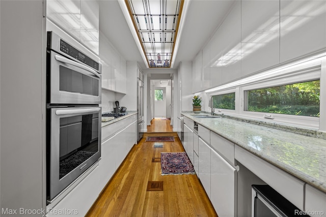 680 Willits St, Birmingham, MI 48009 - kitchen featuring appliances with stainless steel finishes, white cabinets, modern cabinets, light wood-type flooring, and light stone counters