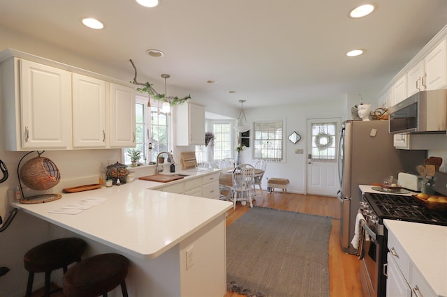 1052 E Rowland St, Grand Blanc, MI 48507 - kitchen with stainless steel appliances, a peninsula, a breakfast bar area, white cabinetry, and recessed lighting