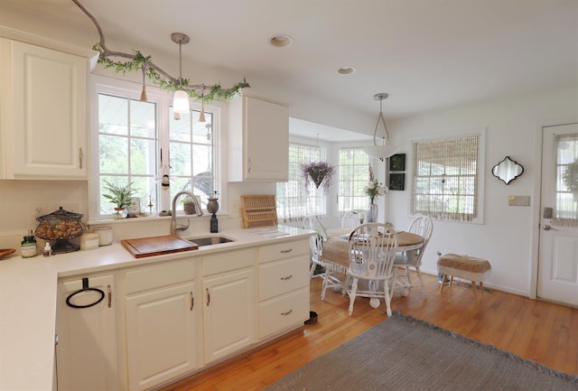 1052 E Rowland St, Grand Blanc, MI 48507 - kitchen with decorative light fixtures, light wood-type flooring, white cabinets, light countertops, and recessed lighting