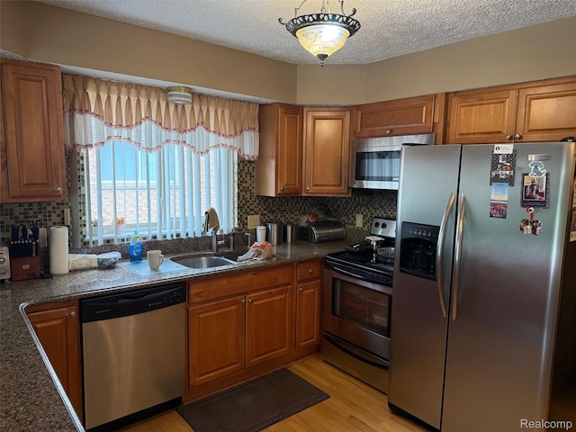 47851 Goldridge Ln, Macomb, MI 48044 - kitchen featuring stainless steel appliances, brown cabinets, tasteful backsplash, light wood-style floors, and a textured ceiling