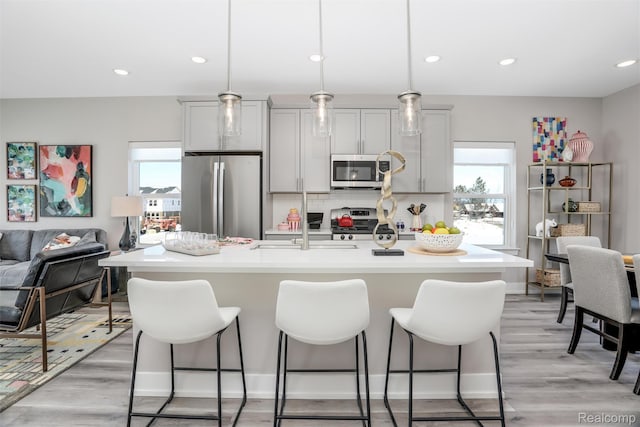 4837 Lismore Ln, Troy, MI 48085 - kitchen with appliances with stainless steel finishes, a kitchen breakfast bar, light countertops, an island with sink, and tasteful backsplash