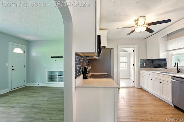 2121 Chesley Dr, Sterling Heights, MI 48310 - kitchen with appliances with stainless steel finishes, a textured ceiling, light wood-type flooring, white cabinets, and decorative backsplash