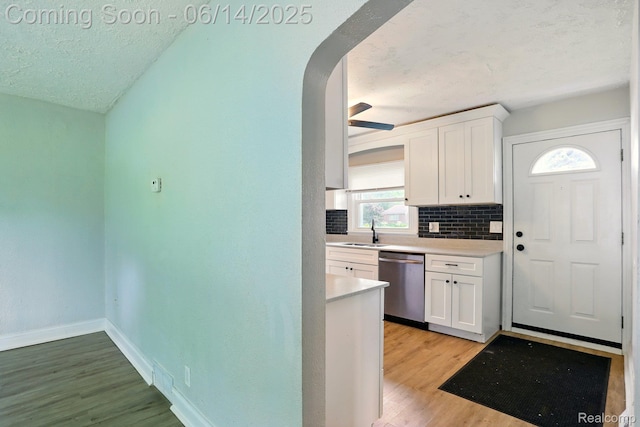 2121 Chesley Dr, Sterling Heights, MI 48310 - kitchen with dishwasher, a textured ceiling, white cabinetry, backsplash, and light countertops