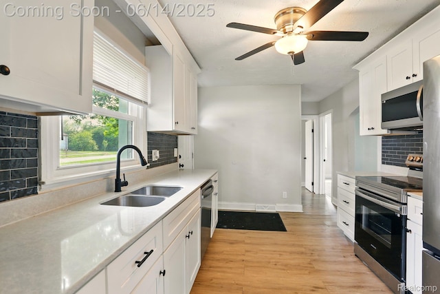 2121 Chesley Dr, Sterling Heights, MI 48310 - kitchen with stainless steel appliances, white cabinets, decorative backsplash, light wood-style floors, and a ceiling fan