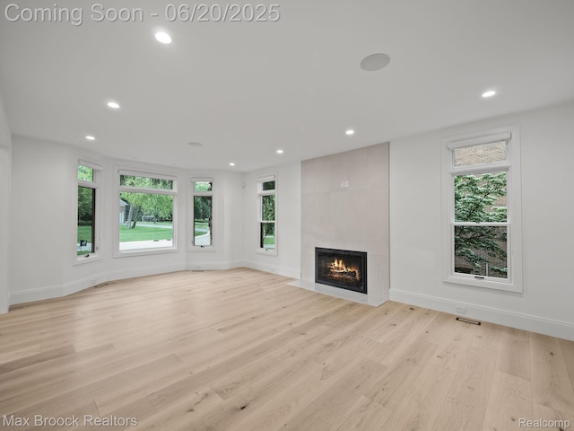 4331 Spruce Hill Ln, Birmingham, MI 48301 - unfurnished living room featuring recessed lighting, plenty of natural light, a tiled fireplace, and light wood-style flooring