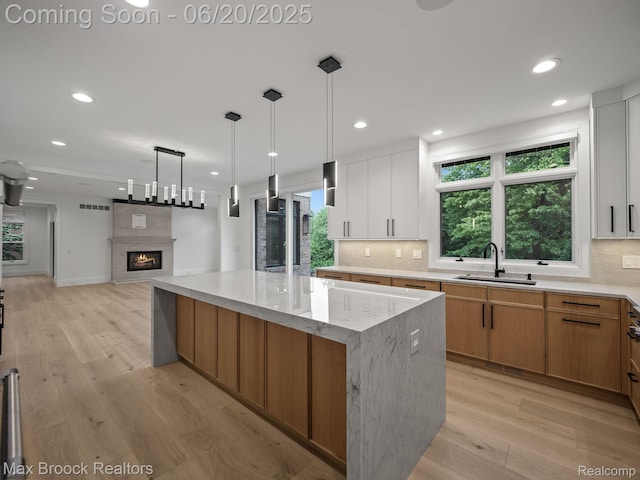 4331 Spruce Hill Ln, Birmingham, MI 48301 - kitchen with a spacious island, decorative backsplash, light wood-style floors, a large fireplace, and recessed lighting