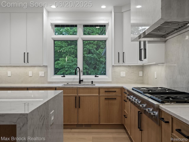 4331 Spruce Hill Ln, Birmingham, MI 48301 - kitchen featuring wall chimney range hood, stainless steel gas stovetop, light stone counters, light wood finished floors, and white cabinetry