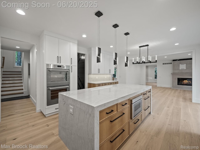 4331 Spruce Hill Ln, Birmingham, MI 48301 - kitchen with stainless steel double oven, light wood-style flooring, light stone countertops, recessed lighting, and white cabinets