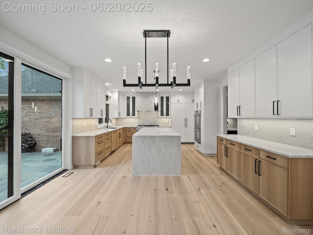 4331 Spruce Hill Ln, Birmingham, MI 48301 - kitchen featuring a center island, light wood-style flooring, tasteful backsplash, glass insert cabinets, and white cabinetry