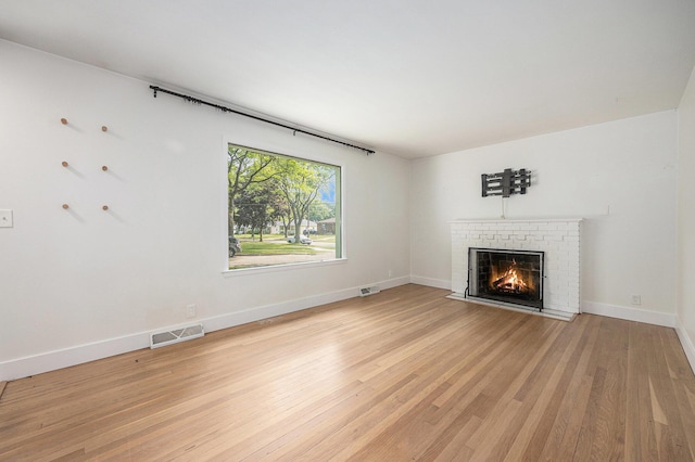 1102 Spencer St NE, Grand Rapids, MI 49505 - unfurnished living room featuring a brick fireplace and light wood-type flooring