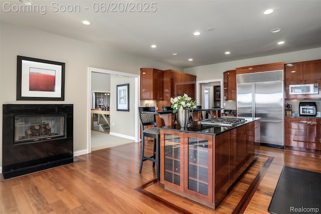5007 Rockaway Ln, Clarkston, MI 48348 - kitchen featuring built in appliances, dark countertops, dark wood-style floors, a breakfast bar area, and a center island
