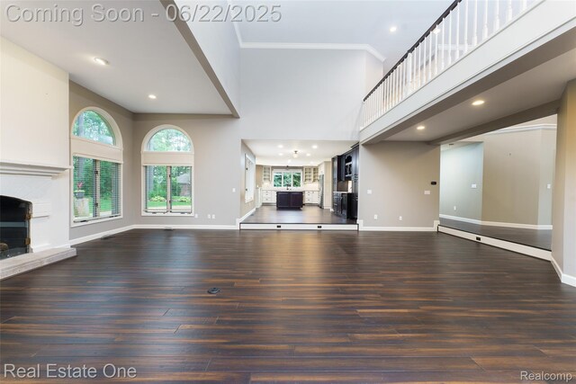 5258 Hidden Pines Dr, Brighton, MI 48116 - unfurnished living room featuring a high ceiling, plenty of natural light, wood finished floors, a fireplace with raised hearth, and recessed lighting