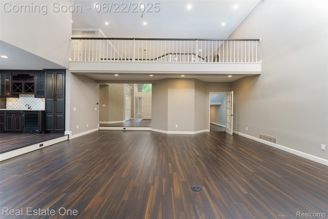 5258 Hidden Pines Dr, Brighton, MI 48116 - unfurnished living room with bar area, a towering ceiling, dark wood-type flooring, and recessed lighting