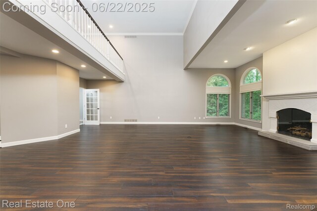 5258 Hidden Pines Dr, Brighton, MI 48116 - unfurnished living room featuring a fireplace with raised hearth, wood finished floors, ornamental molding, and recessed lighting