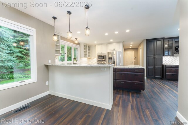 5258 Hidden Pines Dr, Brighton, MI 48116 - kitchen with appliances with stainless steel finishes, a peninsula, backsplash, plenty of natural light, and recessed lighting