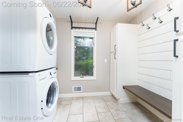 5258 Hidden Pines Dr, Brighton, MI 48116 - laundry room featuring stacked washer and clothes dryer, cabinet space, and light tile patterned floors
