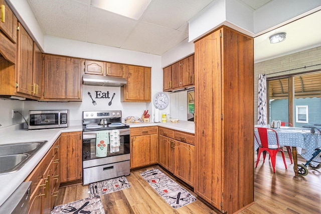 59 Dunning Ave, Battle Creek, MI 49037 - kitchen featuring appliances with stainless steel finishes, under cabinet range hood, a paneled ceiling, light wood finished floors, and light countertops
