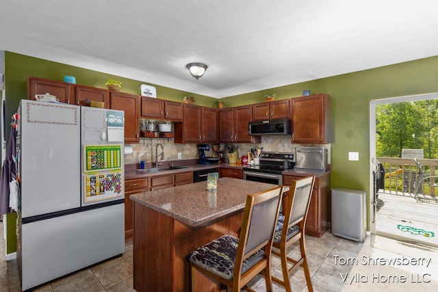 16304 Trent Ridge Dr, Cedar Springs, MI 49319 - kitchen featuring appliances with stainless steel finishes, a breakfast bar area, tasteful backsplash, and a kitchen island