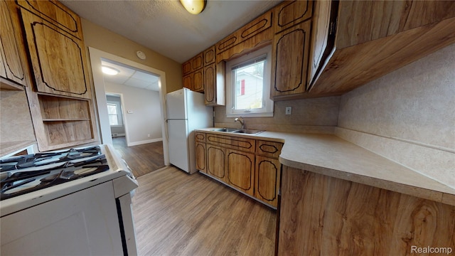 929 Kettering Ave, Pontiac, MI 48340 - kitchen with white appliances, light wood-style flooring, brown cabinetry, light countertops, and healthy amount of natural light