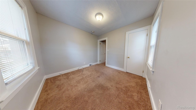 929 Kettering Ave, Pontiac, MI 48340 - unfurnished bedroom with multiple windows, light colored carpet, and a textured ceiling