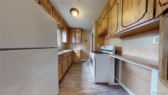 929 Kettering Ave, Pontiac, MI 48340 - kitchen with white appliances, brown cabinetry, wood finished floors, light countertops, and a textured ceiling