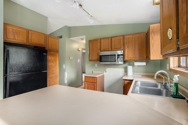 2250 Peters Rd, Ann Arbor, MI 48103 - kitchen featuring stainless steel microwave, freestanding refrigerator, vaulted ceiling, rail lighting, and brown cabinets