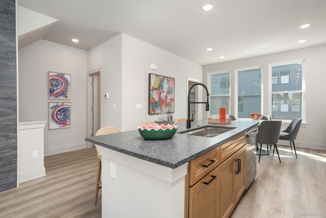 2133 Evergreen Ln Unit 28, Ann Arbor, MI 48103 - kitchen featuring stainless steel dishwasher, light wood-style flooring, an island with sink, dark countertops, and a breakfast bar