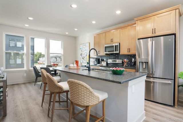 2133 Evergreen Ln Unit 28, Ann Arbor, MI 48103 - kitchen featuring appliances with stainless steel finishes, light brown cabinets, dark countertops, light wood-style flooring, and a kitchen breakfast bar