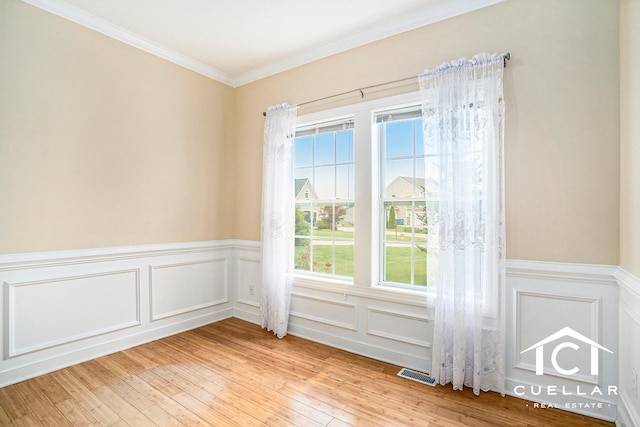 9365 Windward Dr, West Olive, MI 49460 - spare room featuring plenty of natural light, a wainscoted wall, light wood-type flooring, ornamental molding, and a decorative wall