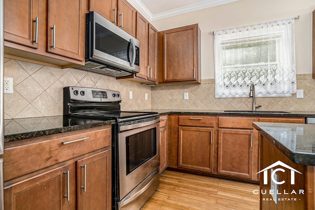 9365 Windward Dr, West Olive, MI 49460 - kitchen with appliances with stainless steel finishes, ornamental molding, dark stone countertops, brown cabinets, and light wood finished floors