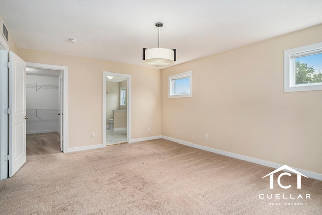 9365 Windward Dr, West Olive, MI 49460 - unfurnished bedroom with light colored carpet, a walk in closet, ensuite bath, and a closet