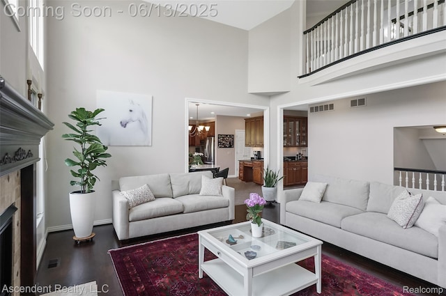 48392 Binghampton Dr, Northville, MI 48168 - living room featuring a fireplace, a towering ceiling, wood finished floors, and a chandelier