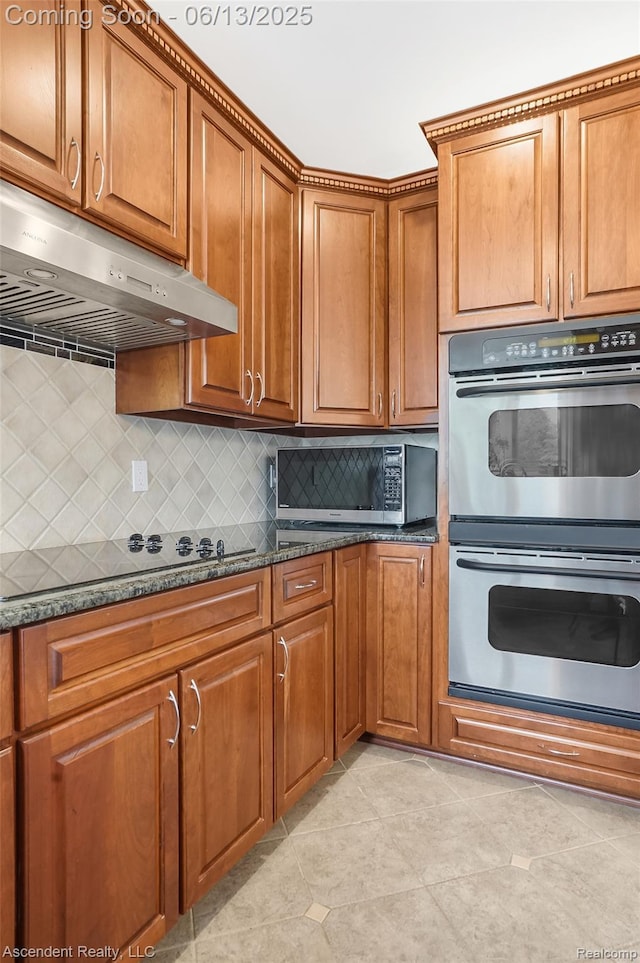 48392 Binghampton Dr, Northville, MI 48168 - kitchen featuring appliances with stainless steel finishes, exhaust hood, brown cabinets, decorative backsplash, and light tile patterned floors