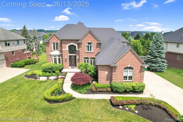48392 Binghampton Dr, Northville, MI 48168 - view of front facade with brick siding, a front yard, concrete driveway, and roof with shingles