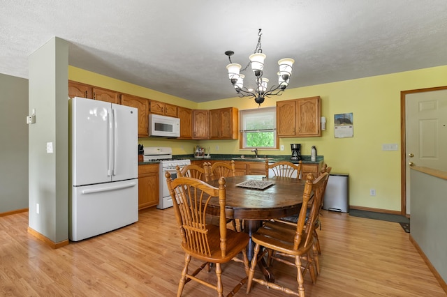 14244 36th St, Gobles, MI 49055 - kitchen featuring white appliances, dark countertops, a chandelier, light wood-style flooring, and brown cabinets