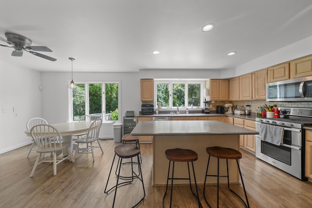 7624 Quail Ridge Dr, Dexter, MI 48130 - kitchen featuring appliances with stainless steel finishes, plenty of natural light, a kitchen bar, light wood-style flooring, and recessed lighting