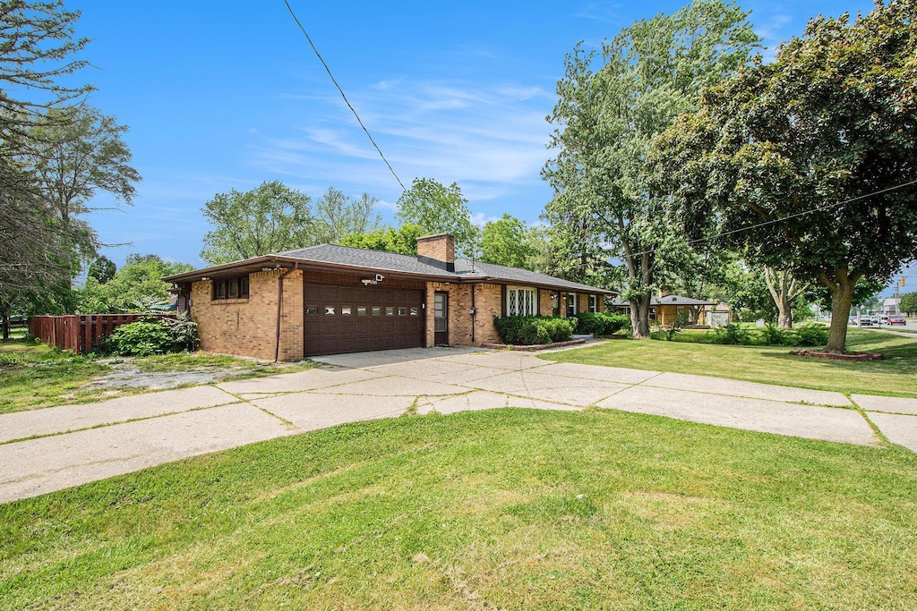 4785 Kalamazoo Ave SE, Kentwood, MI 49508 - view of front of home featuring a garage, concrete driveway, brick siding, and a chimney