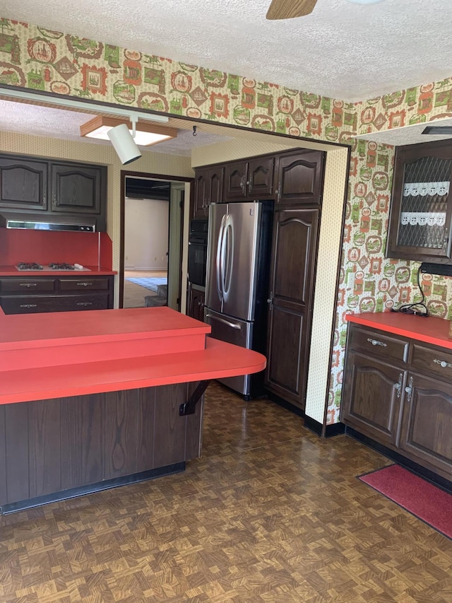 5513 S Waverly Rd, Lansing, MI 48911 - kitchen featuring freestanding refrigerator, black oven, a textured ceiling, gas stovetop, and wallpapered walls